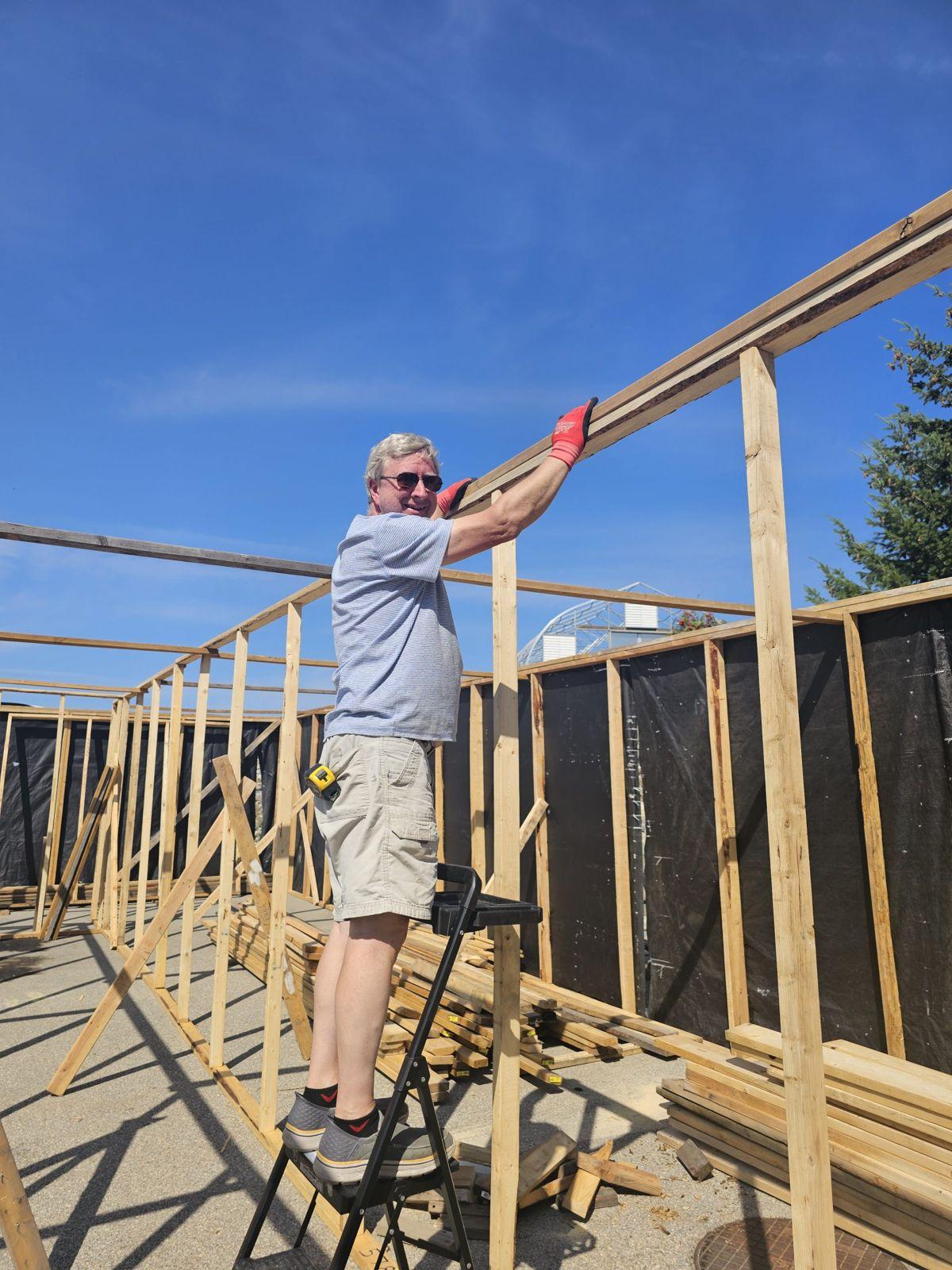 A volunteer raising rafters against a blue sky