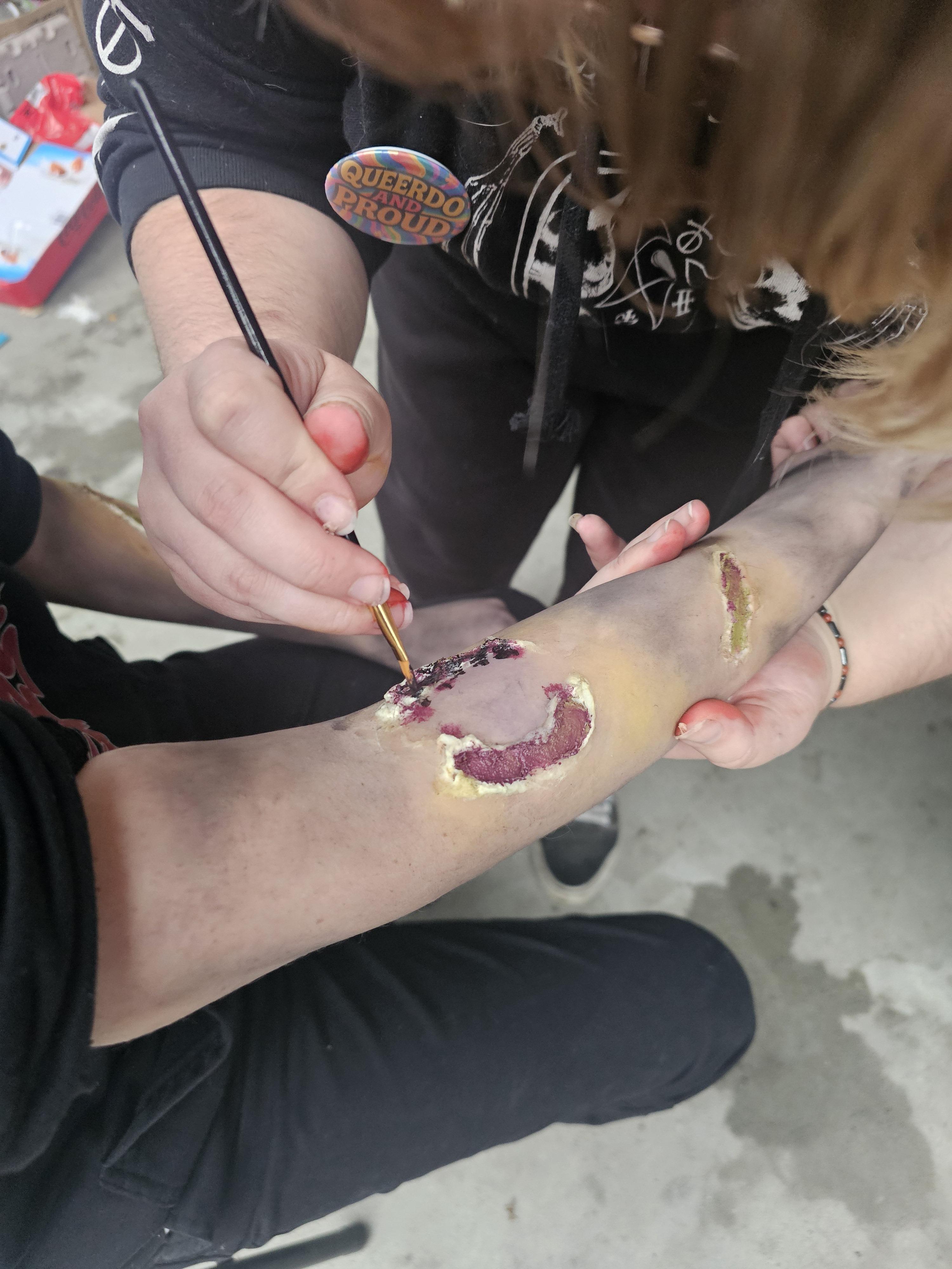 A makeup artist painting a wound prosthetic