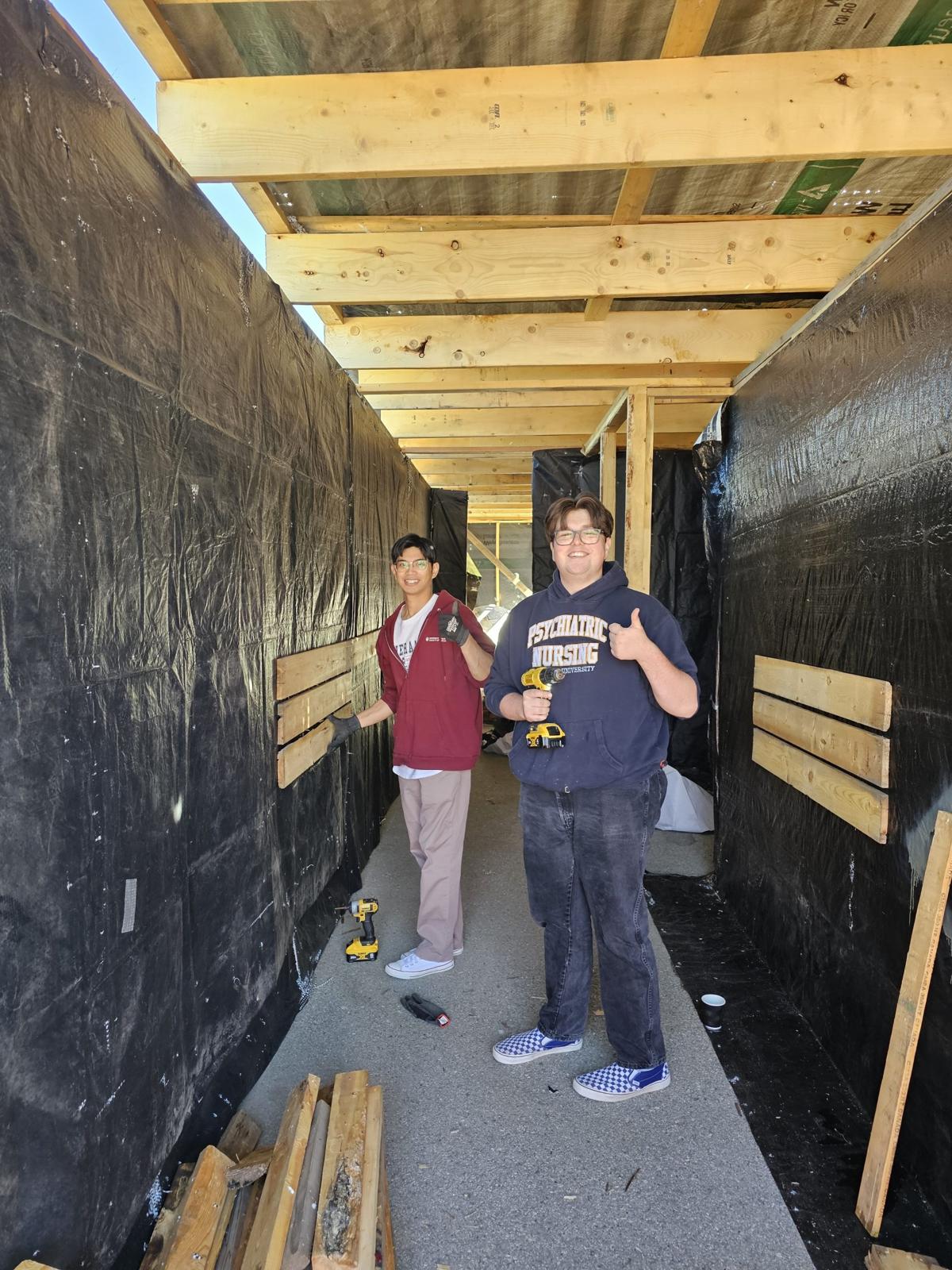 Two volunteers giving thumbs up inside the corridor build